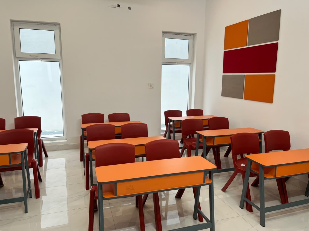 Bright classroom with orange desks and acoustic panels at B-17 Campus